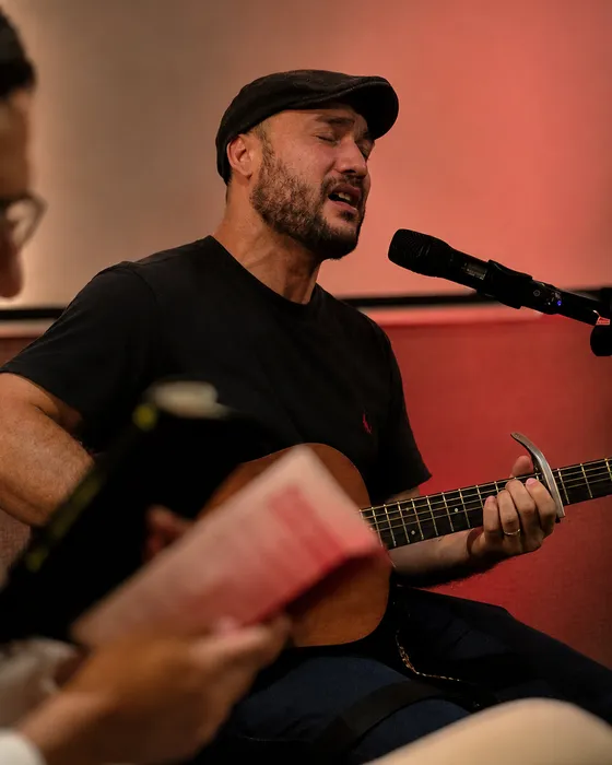 Luan Saints cantando e tocando violão, de olhos fechados